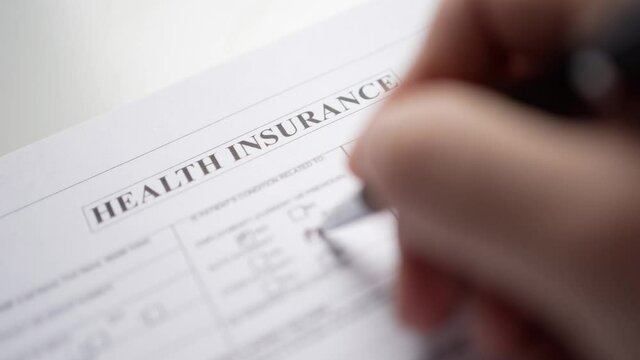 Filling a Health Insurance Document By Hand Closeup