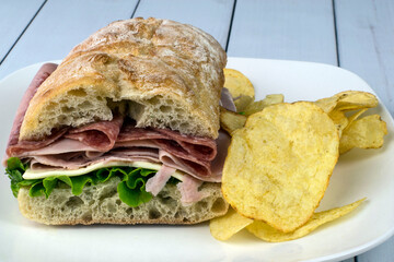 ham and salami sandwich with potato chips