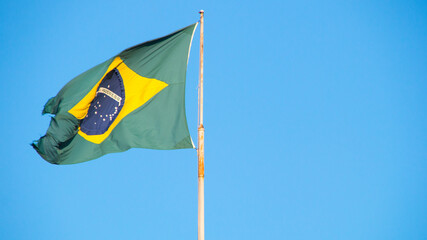 Flag of Brazil outdoors with a beautiful blue sky in the background in Rio de Janeiro.
