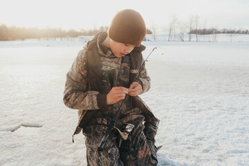 boy ice fishing on a pond in the winter