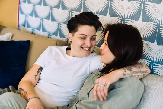 Happy lesbian couple cuddling on couch 