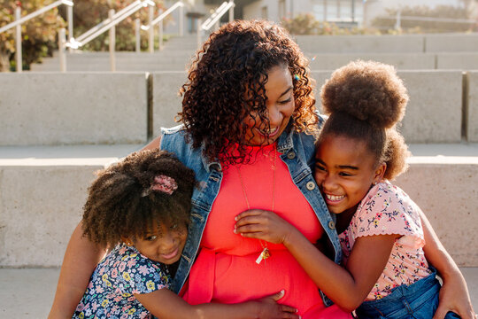 Loving Black mom hugging daughters