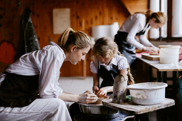 Kid having pottery lesson with skilled master