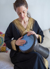 Female drummer wearing a traditional arabic clothes playing darbuka percussion instrument.