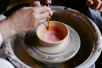 Artist decorating pot by paints 