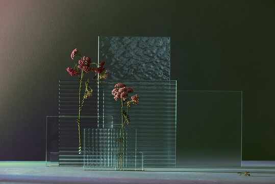 Ribbed and gloss glass with purple butterfly weed  on dark background.
