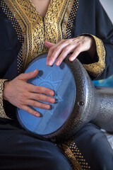 Female drummer wearing a traditional arabic clothes playing darbuka percussion instrument.