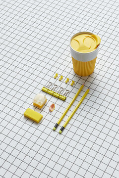 Yellow coffee cup, paper clips, pins, eraser, pencils and sharpener
