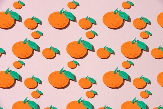 Fruit made of paper. Seamless pattern from oranges on a pink background.