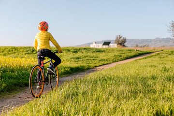Anonymous teenager riding bicycle along sandy road