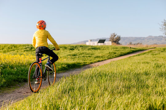 Anonymous teenager riding bicycle along sandy road