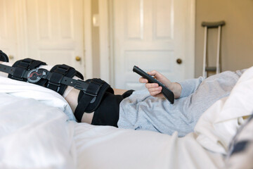 Recuperating woman holds tv remote recovering at home