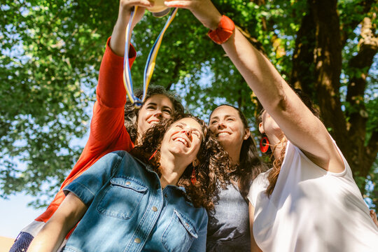 Happy girlfriends taking selfie on photo camera in park