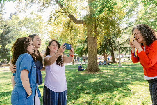 Happy girlfriends taking selfie on photo camera in park