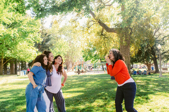 Happy girlfriends taking selfie on photo camera in park