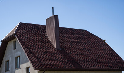 Brown corrugated metal profile roof installed on a modern house. The roof of corrugated sheet. Roofing of metal profile wavy shape. Modern roof made of metal. Metal roofing.