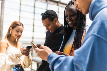 Multiracial friends browsing smartphones on street