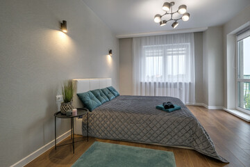  Interior of the modern luxure bedroom in studio apartments in gray light color style and green pillows