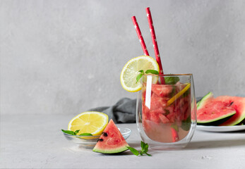Cold Bright Watermelon Mojito cocktail with mint, lemon slices and drinking straw on light background with place for text
