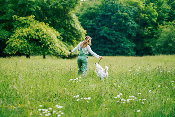 A happy woman running with her dog in a park
