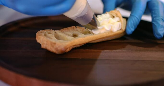 Chef with confectionery bag stuffing the eclair with choux cream. Homemade eclairs. Squeezing vanilla cream in eclair and profiteroles. The filling for the eclairs extruded from a pastry bag.
