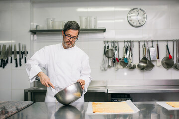 Chef kneading dough in bowl working in modern kitchen 
