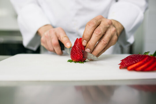 Chef slicing strawberries with kitchen knife