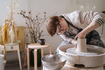 Craftswoman creating clay pot on wheel