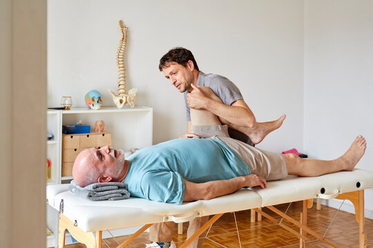 An osteopath holding patient's bent leg