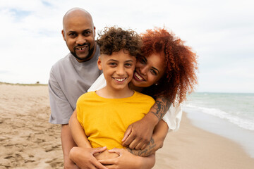 Happy family hugging their teen son looking at camera 