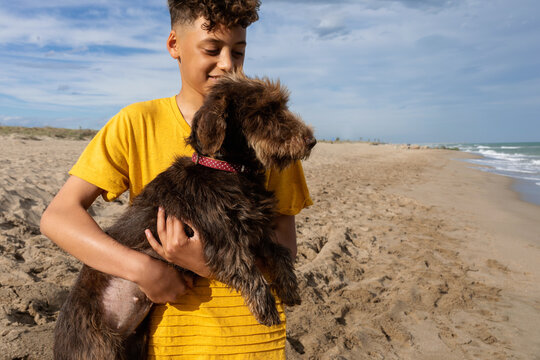 Little boy having fun with his dog on the beach