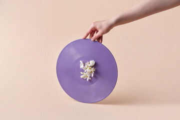 Woman holding violet vinyl record with flowers