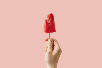 Woman holding bitten strawberry ice cream on stick