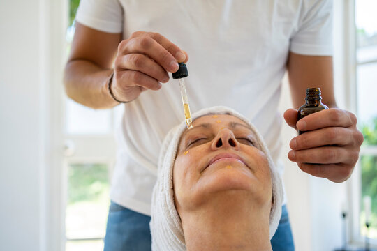Male hands applying facial serum to an aged face