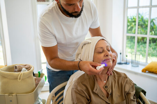 Senior woman getting a facial massage at home