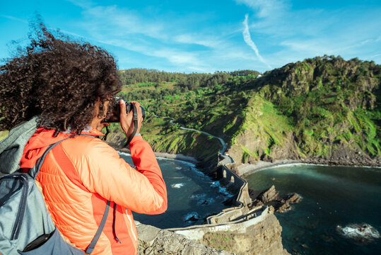 Female traveler taking picture of cliff in sea