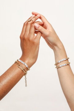 Two female hands with jewelry on holding each other
