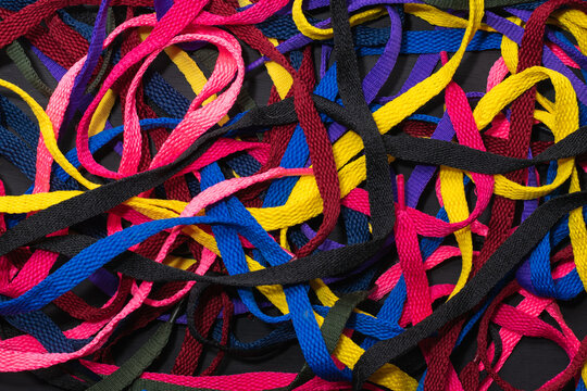 colorful shoelaces background, on black wood, messy, clutter concept, advertisement © Mauricio Toro