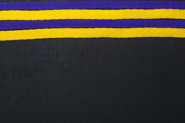 yellow and purple shoelaces, lakers flag, on black wooden background, leaving space for advertising...