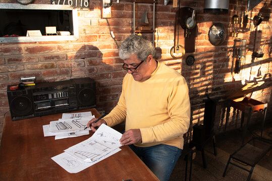 un hombre dibuja el dise&ntilde;o de un objeto a construir artesanlamnte para vender en su comercio