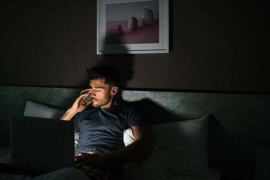 Tired Man In Pajamas Watching Movies On The Computer