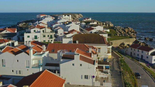 Baleal, Portugal, Europe. Drone footage of turquoise and bluish sea waters washing remote island. Beautiful coastal cottages with a seascape in the background. High quality 4k footage