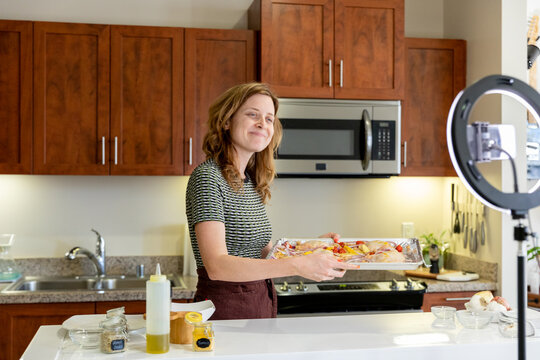 Woman Smiles at Phone Recording Holding a Baking Sheet