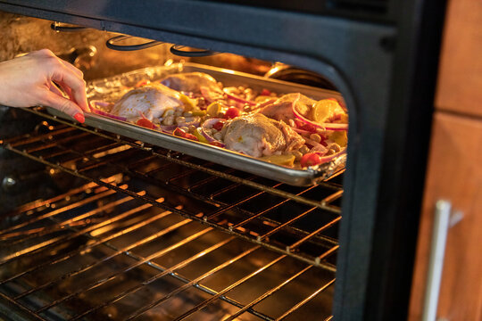 Woman Slides Chicken into Oven.
