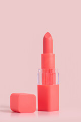 Coral lipstick on pink background. Pink lipstick in a lid of the same color with a cap next to it. Cosmetics for lips with delicate and bright tones. Make up element.