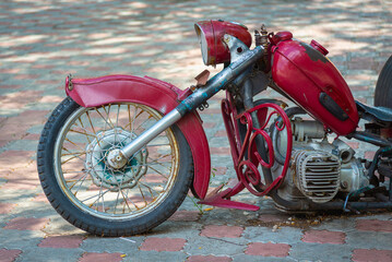 Old red motorcycle in the park.