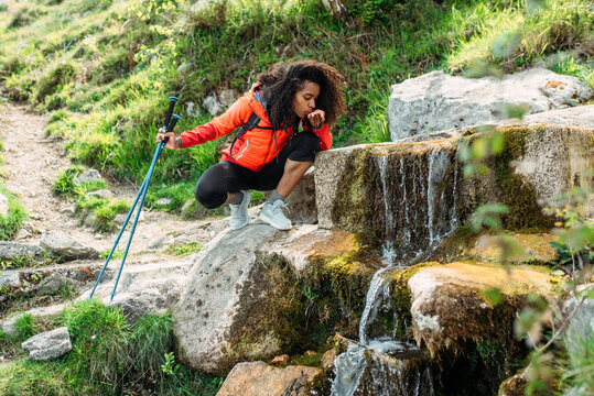 Black tourist drinking water from creek