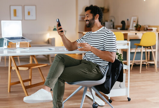 Happy man browsing smartphone at workplace