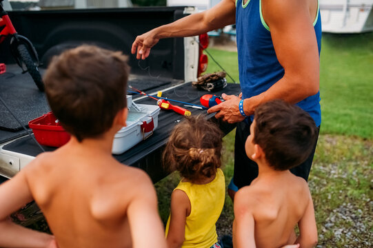 Kids watching their dad get fishing poles ready. 