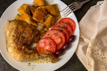 Stewed chicken leg and sweet potatoes (Ipomoea batatas) lie on a white plate close-up